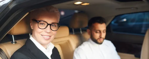 Deux passagers à l’arrière d’une voiture, une femme en lunettes au premier plan.