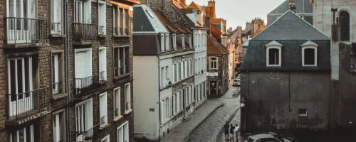 Rue bordée de façades anciennes et de toits en pente.