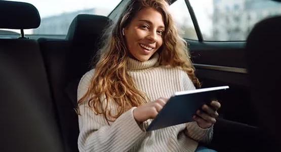 Passagère utilisant une tablette à l’arrière d’une voiture.
