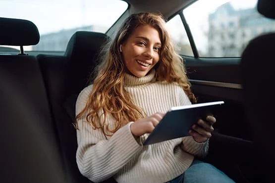 Passagère utilisant une tablette à l’arrière d’une voiture.