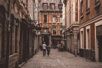 Rue pavée bordée de façades anciennes avec des passants.