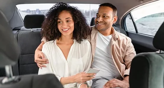 Deux passagers souriants à l’arrière d’une voiture.