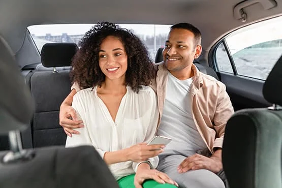 Deux passagers souriants à l’arrière d’une voiture.