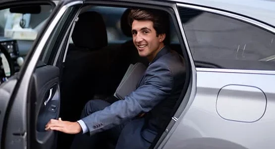 Homme en costume sortant d’une voiture grise.