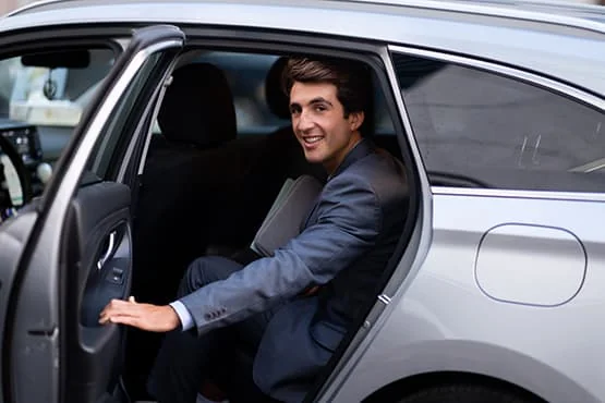 Homme en costume sortant d’une voiture grise.