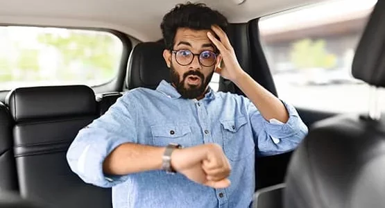 Passager regardant sa montre avec une main sur le front à l’arrière d’une voiture.