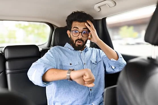 Passager regardant sa montre avec une main sur le front à l’arrière d’une voiture.