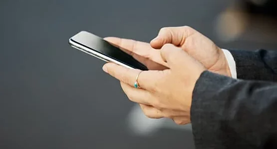 Personne utilisant un téléphone tenu à deux mains.
