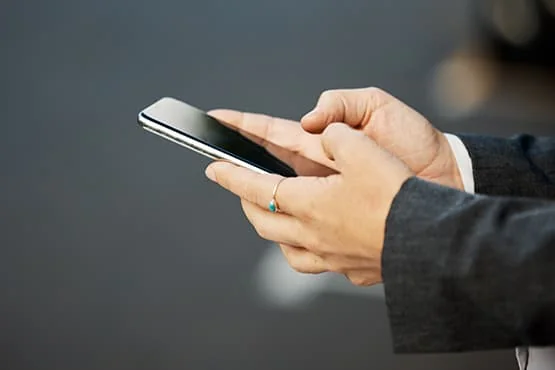 Personne utilisant un téléphone tenu à deux mains.
