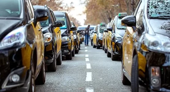 Files de voitures de taxi noires et jaunes dans une rue.