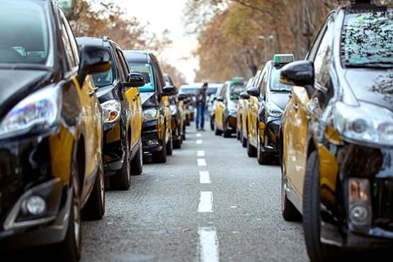 Files de voitures de taxi noires et jaunes dans une rue.